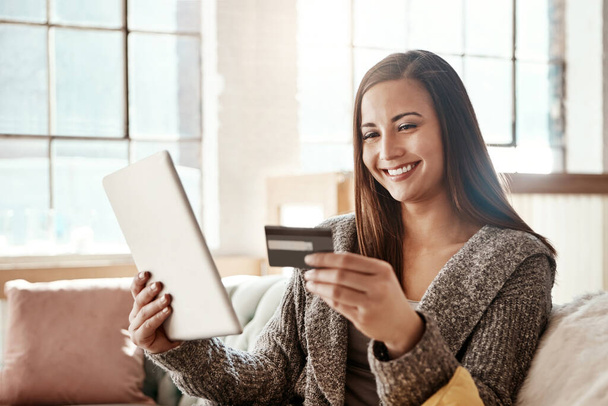 Tablet, online shopping and credit card, happy woman on couch on retail app and internet banking in home. Technology, cashback payment and girl on sofa with smile on ecommerce website or digital shop. - 写真・画像