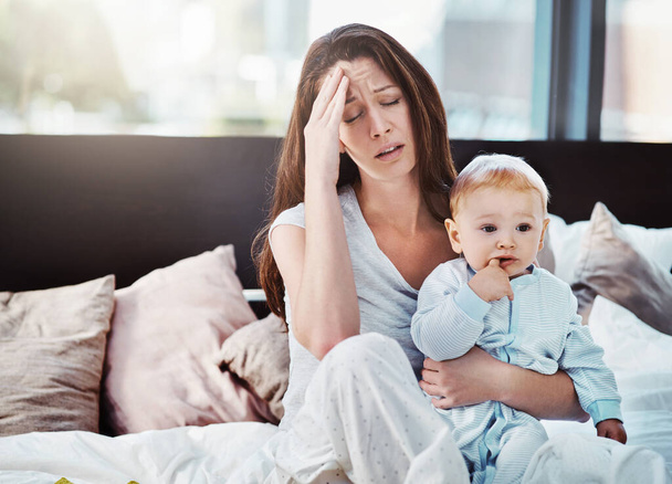 Mother, baby and tired or stress in a home bedroom or bed with postpartum, headache or anxiety. Depression, mental health and burnout of a woman or mom with a child in a family house with fatigue. - Fotoğraf, Görsel