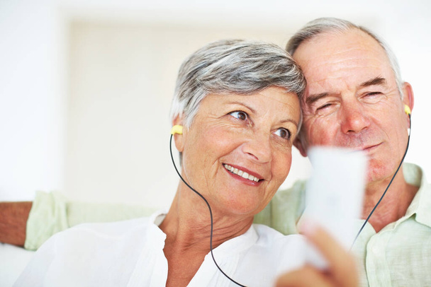 Ältere Paare hören zusammen Musik. Nahaufnahme eines glücklichen, reifen Paares, das zu Hause gemeinsam Musik hört - Foto, Bild