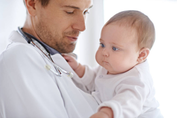 Doctor, pediatrician and holding baby for healthcare assessment, medical support and growth. Newborn kids, man and pediatrics service in clinic, hospital or expert consulting for wellness of children. - Photo, image