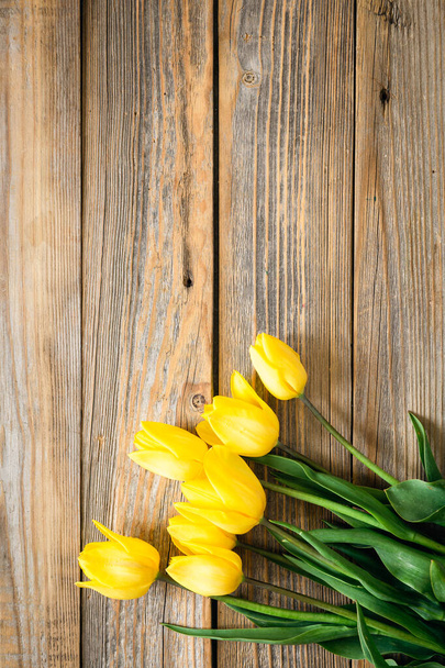 Ανοιξιάτικο φόντο με κίτρινες τουλίπες σε ξύλινο φόντο, πάνω όψη, αντιγραφή χώρου. - Φωτογραφία, εικόνα