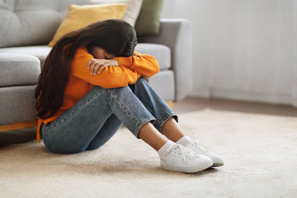 Depressionen. Porträt einer aufgebrachten jungen Frau aus dem Mittleren Osten, die zu Hause weint, deprimierte Millennial Lady, die Kopf in Knie vergräbt, auf dem Fußboden im Zimmer sitzt, einen Nervenzusammenbruch erleidet, Kopierraum - Foto, Bild