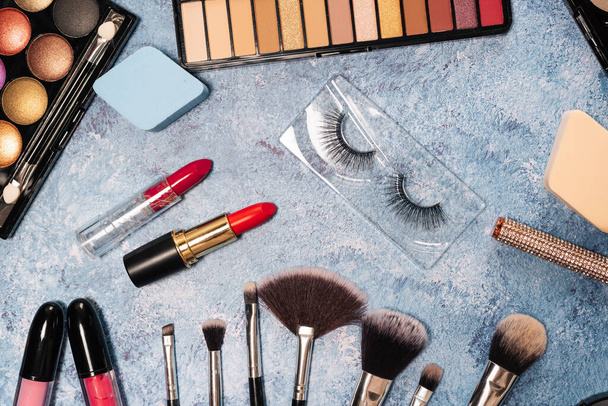 conjunto de cosméticos decorativos, maquiagem escova pestanas falsas fundo azul. vista de cima - Foto, Imagem