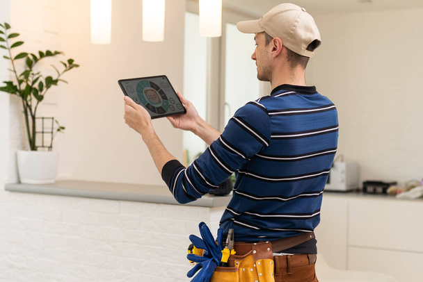 Electrician with tablet indoors, lamp. - Foto, Bild