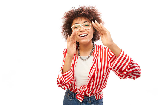 Portrait of curly brunette young woman screaming into her palms on white studio background. Important information, news concept - Foto, afbeelding