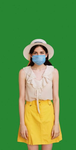 Summer quarantine. Pandemic depression. Flu prevention. Displeased upset woman in protective medical mask in bad mood isolated green copy space background. - Foto, immagini