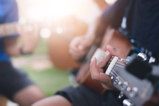 Κοντινό πλάνο των χεριών ενός νεαρού που παίζει ακουστική κιθάρα - Φωτογραφία, εικόνα