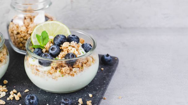 Yoğurt, kireç ve yaban mersinli gevrek, sağlıklı atıştırmalık veya Parlak Arkaplanda Kahvaltı - Fotoğraf, Görsel