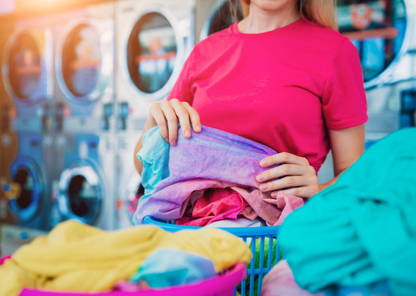 Young beautiful woman washes and dries clothes in the laundry. - Foto, Imagen