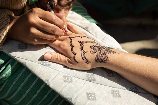 The artist applies a fantasy henna drawing to a womans hand. High quality photo - Foto, Bild