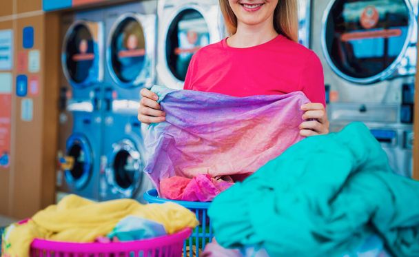 Young beautiful woman washes and dries clothes in the laundry. - Foto, afbeelding