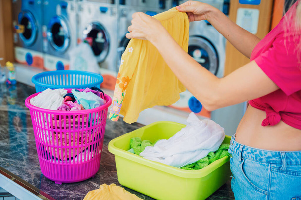 Young beautiful woman washes and dries clothes in the laundry. - Foto, imagen