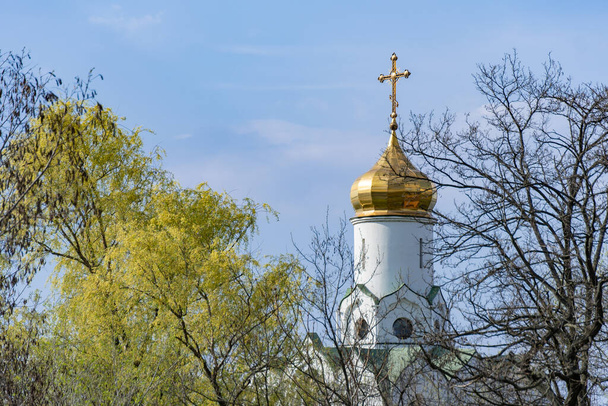 Church saint Nicholas with golden domes and place religion of orthodox christian. Built structure for prayer in modern city. Landscape with green park in middle of river. Monastyrsky island in Dnipro. - Photo, Image