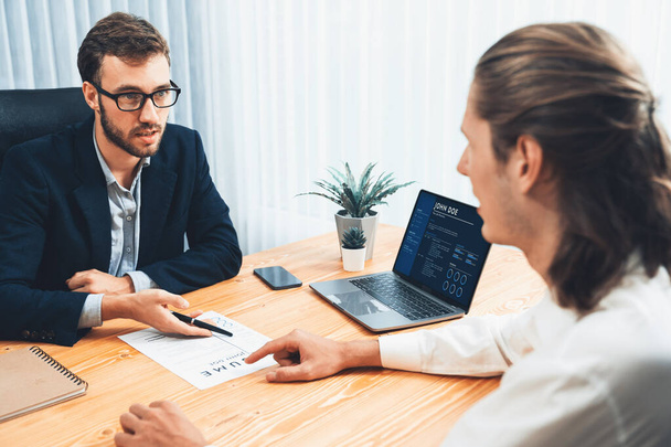 Job candidate engaging conversation with interviewer during job interview. Job applicant present work experience and qualification by digital resume on laptop and CV paper to HR manager. Entity - Foto, Bild