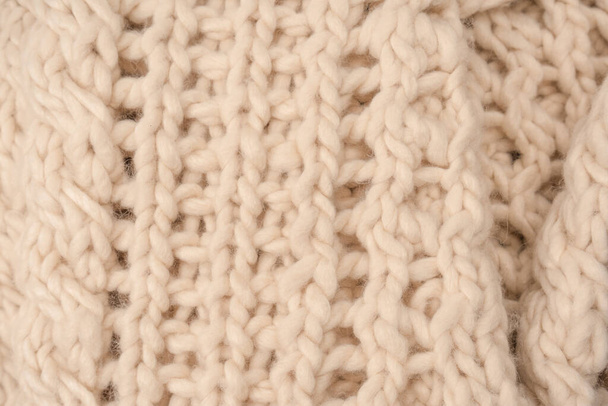 A fragment of beige knitted fabric, knitted from white sheep wool. Knitted background.  - Fotoğraf, Görsel