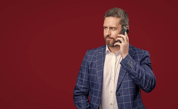 businessman speak on phone. photo of businessman speak on phone. formal businessman speak on phone isolated on red background. businessman in formal menswear speak on phone in studio. - Photo, Image