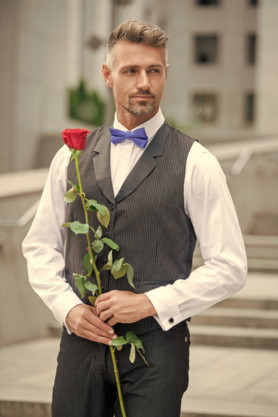 love day concept. elegant tuxedo man with love rose. flower gift for love day. - Foto, Imagen
