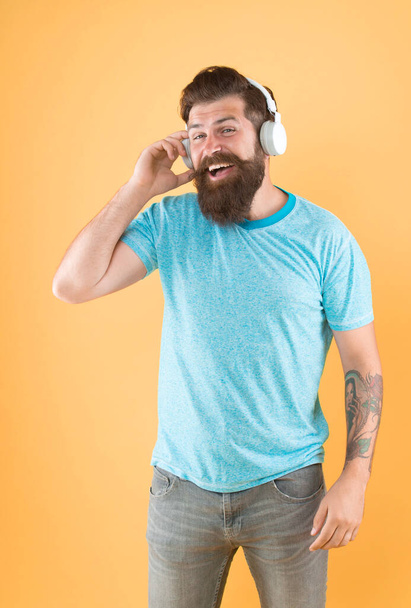Freedom going wireless offers you is unparalleled. Wireless headphones designed to deliver clean sound. Bearded man listening music wireless gadget. Hipster happy using modern wireless headphones. - Foto, Imagem