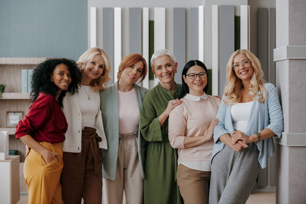Group of mature businesswomen bonding and smiling while standing in the office together - Фото, зображення