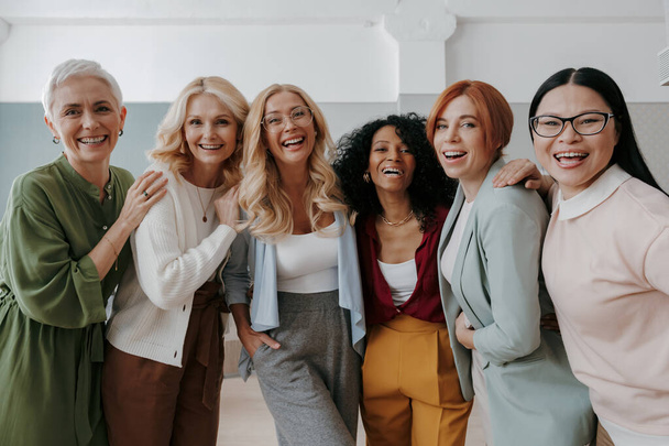 Multi-ethnic group of confident mature women embracing and smiling at camera - Photo, Image
