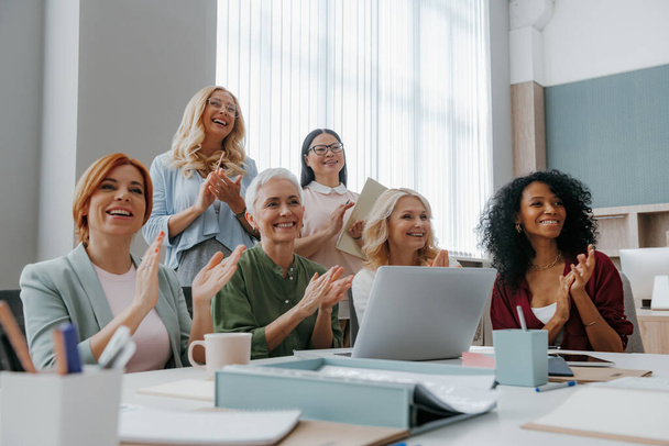 Érett nők csoportja tapsol, miközben üzleti tréningeket tartanak az irodában - Fotó, kép