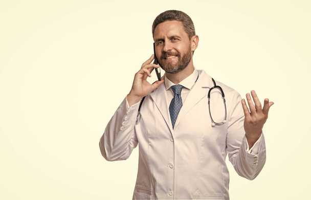 Happy doctor talking on mobile phone. Mobile physician isolated on white. Using mobile technology in healthcare. Ehealth, copy space. - 写真・画像