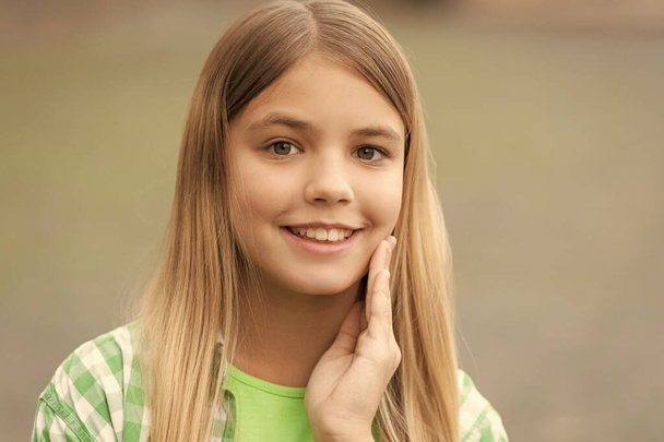 Portrait of happy teenager girl with smiling face holding hand on cheek blurry outdoors. - Fotoğraf, Görsel
