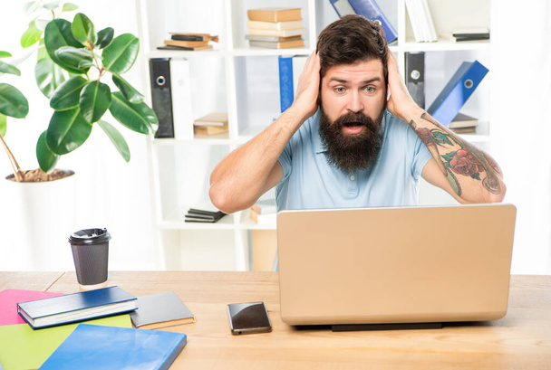 Shocked businessman clutching head staring in laptop at office desk, shock. - Photo, image