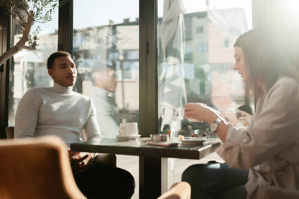 Friends in a restaurant talking smiling and drinking tea. Business colleagues having a meeting after work or during coffee break at a cafe bar. - Foto, imagen