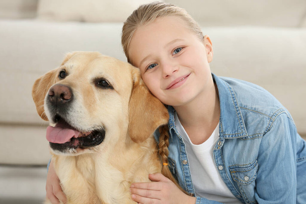 Cute child with her Labrador Retriever indoors. Adorable pet - Photo, image
