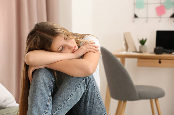 Unhappy teenage girl sitting in room at home - Valokuva, kuva