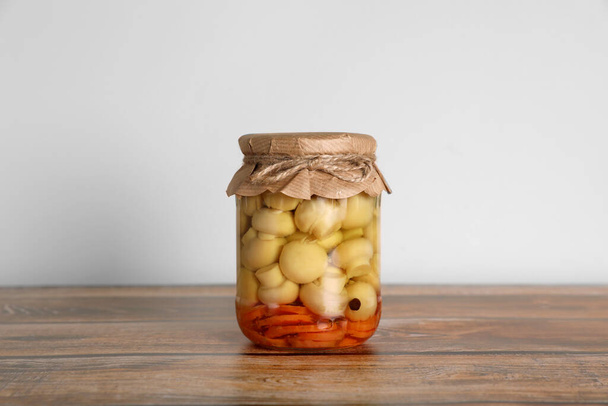 Jar with pickled mushrooms and carrots on wooden table - Photo, Image