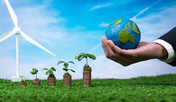 Öko-Unternehmen investieren in den Umweltschutz subventioniert, Münzstapel mit wachsen Sämling, Hand hält Papier Erde und Windturbine. Nachhaltiges Finanzwachstum durch saubere und erneuerbare Energien. Alter - Foto, Bild