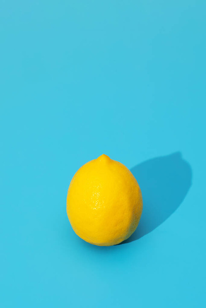 Yellow lemon on a blue background with a hard shadow. Copy space. The concept of summer, fruit. - Foto, immagini