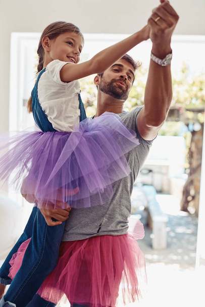 Πατέρας με την κόρη χορεύουν σε tutu, παιχνιδιάρικο και διασκεδαστικό στο σπίτι με τη σύνδεση με την αγάπη και τη φροντίδα Οικογένεια, ο άνθρωπος και το κορίτσι χορεύουν στο σαλόνι, ανέμελη και να περνούν το χρόνο τους μαζί με τη σχέση και τη χαρά. - Φωτογραφία, εικόνα