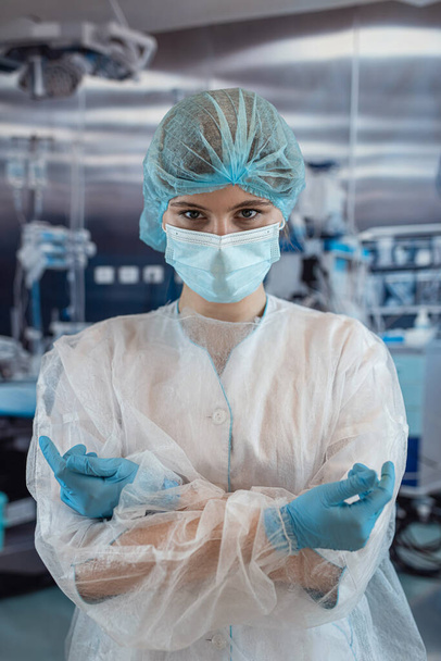 Egy női sebész vagy asszisztens portréja, aki sebészeti maszkot visel a kórház műtőjében. Coronavirus Covid19 világjárvány - Fotó, kép