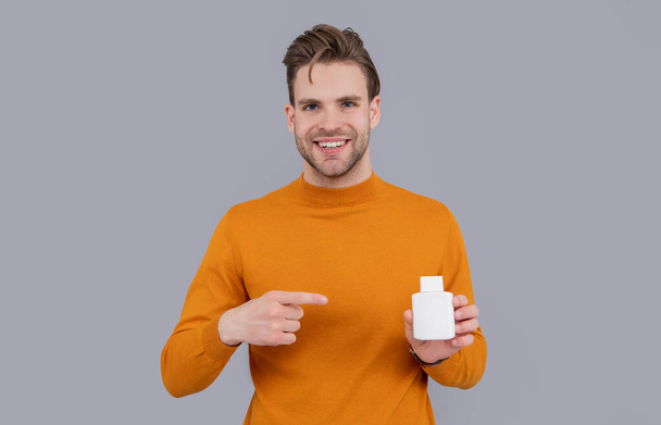 Man pointing finger on bottle. Prescription pill bottle. Medicine bottle for medical or pharmaceutical product. Presenting product in blank plastic bottle advertisement banner, copy space. - Фото, зображення