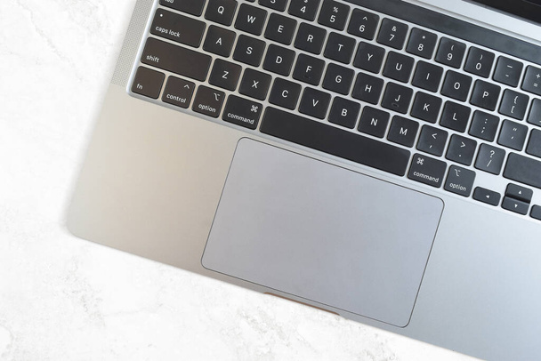 Closeup of laptop keyboard on classy white marble background. Empty space on keyboard works great to add a sticker. - 写真・画像