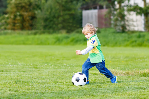 Two little sibling boys playing soccer and football on field - Photo, Image