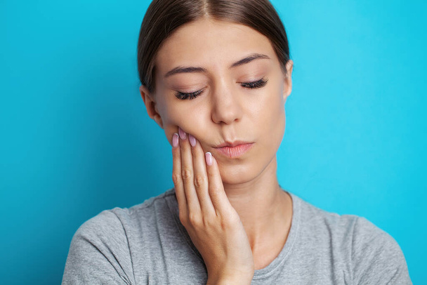 Γυναίκα που υποφέρει από πόνο των δοντιών και αγγίζοντας μάγουλο. - Φωτογραφία, εικόνα