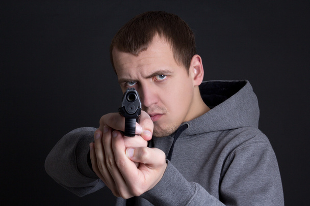 man crimineel gericht met pistool over grijs - Foto, afbeelding