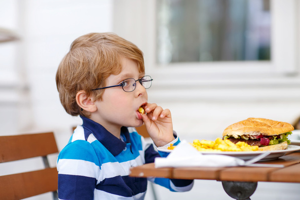 Pikkupoika syö pikaruokaa: ranskalaisia perunoita ja hampurilaisia
 - Valokuva, kuva