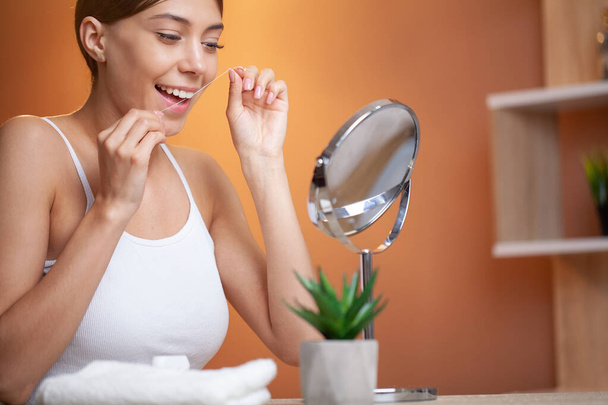Mujer usando hilo dental para limpiar sus dientes
. - Foto, Imagen