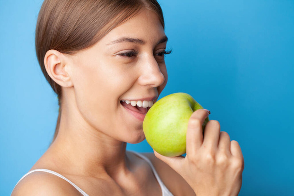 Belle fille avec des dents blanches parfaites tenant la pomme verte sourire. - Photo, image