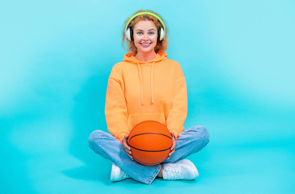 cheerful basketball woman listen music in studio. basketball woman listening music on background. photo of basketball woman loves music. basketball woman loves music isolated on blue. - Φωτογραφία, εικόνα