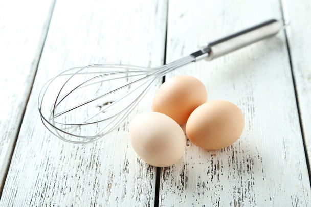 Stainless steel egg whisk with eggs - Fotoğraf, Görsel