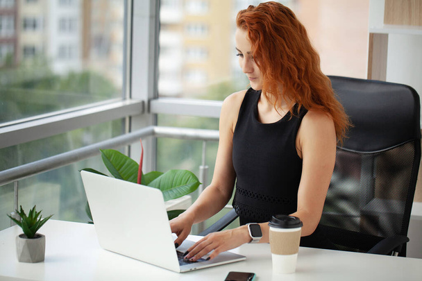 Kaunis hymyilevä nuori punatukkainen liiketoiminnan nainen poseeraa toimistossa - Valokuva, kuva