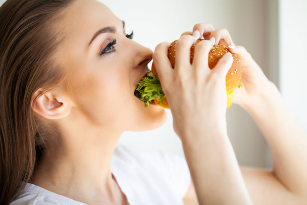Young woman eating hamburger woman eating junk food. - Zdjęcie, obraz