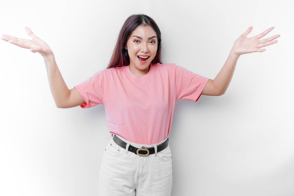 Shocked Asian woman is wearing pink t-shirt with her mouth wide open, isolated by white background - Foto, afbeelding
