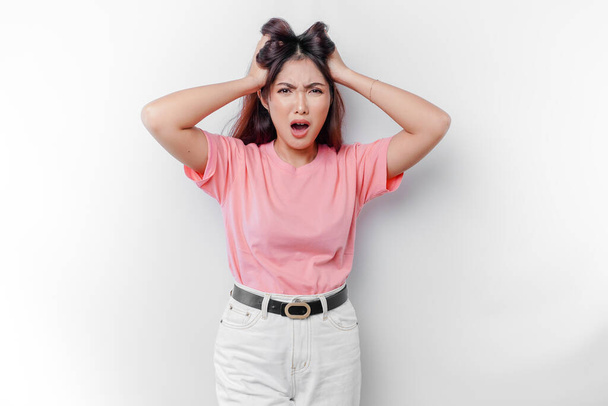 A portrait of an Asian woman wearing a pink t-shirt isolated by white background looks depressed - Photo, Image